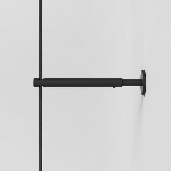 Black metal shower arm with a black braided hose attached to a white wall