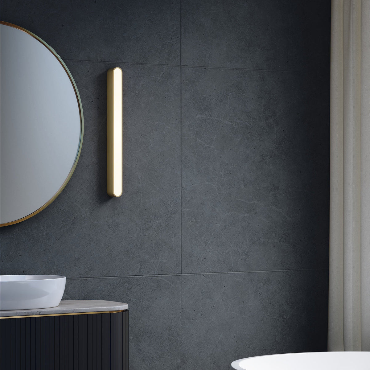 Bathroom with dark grey tiled wall, round mirror, vertical light fixture, and white sink on dark vanity
