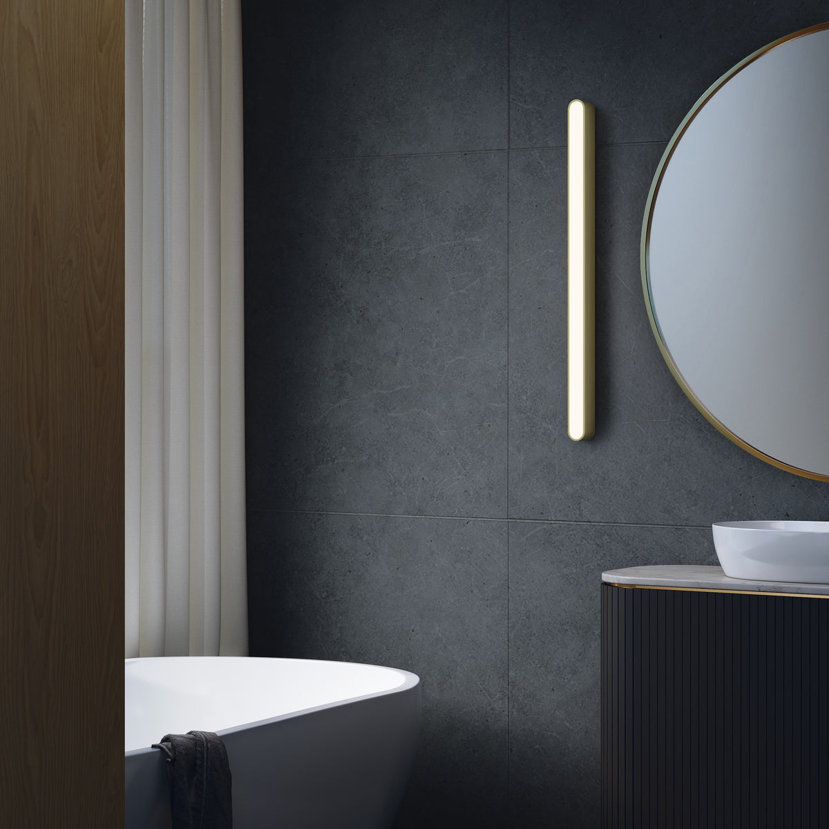 Modern bathroom with dark grey tiled walls, a white freestanding bathtub, and a round mirror with a gold frame