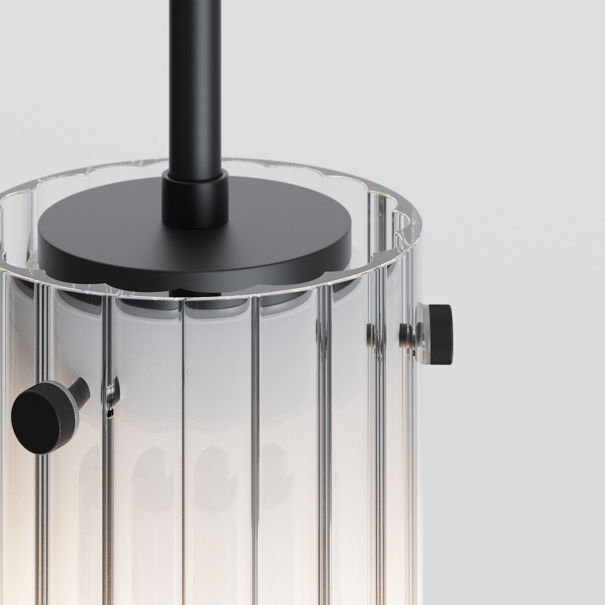 Close up of a clear glass pendant light with vertical ridges and black metal accents