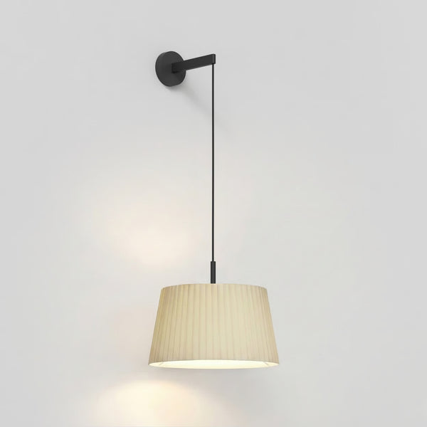 Black wall-mounted light fixture with a long cord and a pleated beige lampshade