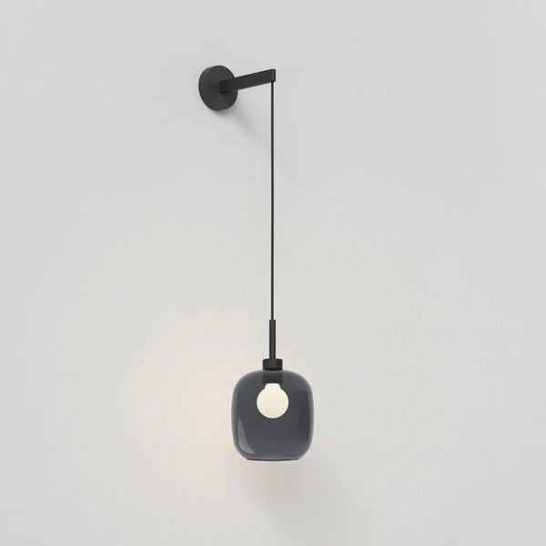 Black wall-mounted light fixture with a dark grey glass shade and exposed bulb