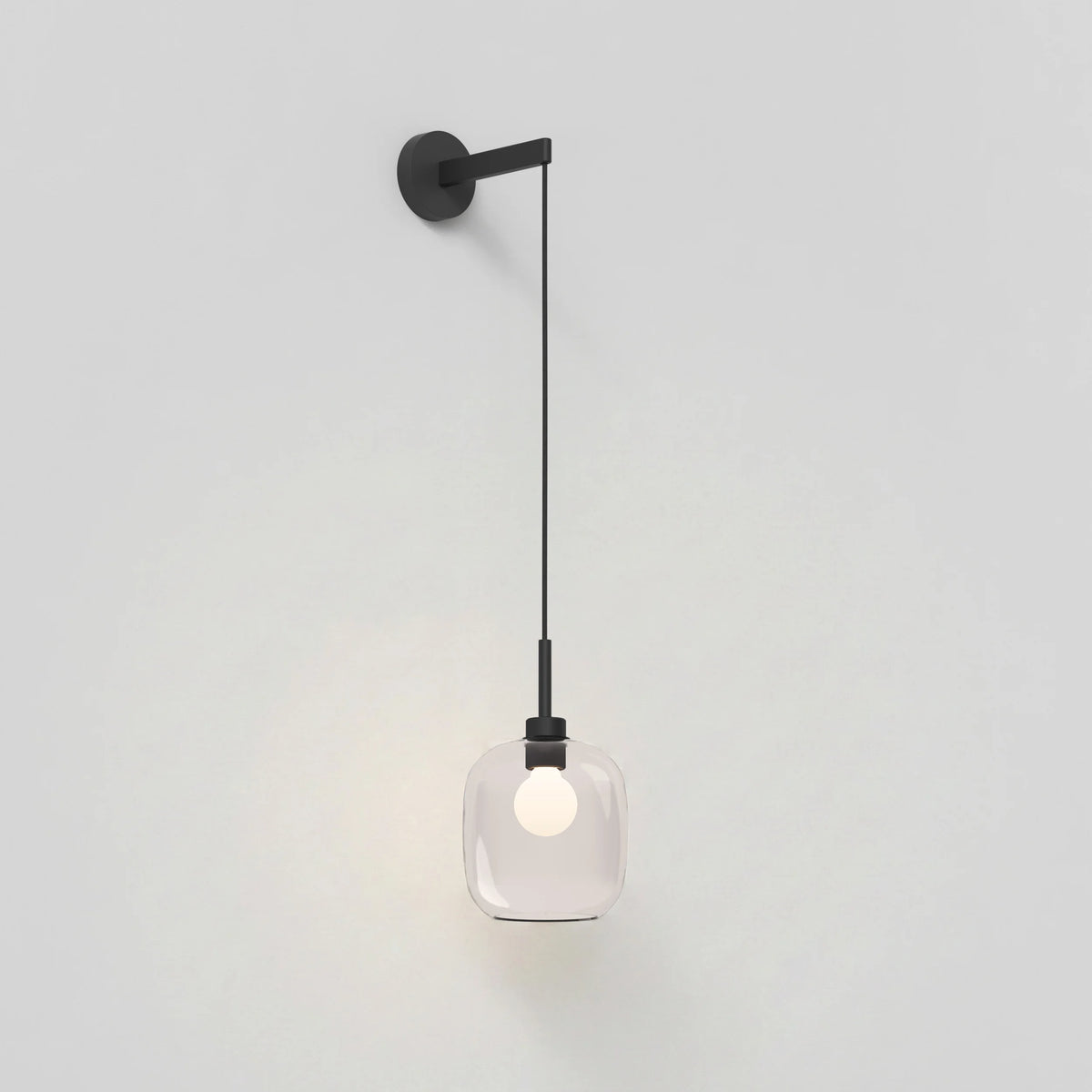 Black wall sconce with a clear glass shade and exposed bulb