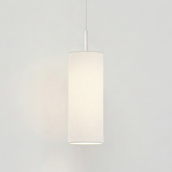White cylindrical pendant light with a fabric shade, hanging from a white ceiling on a thin rod