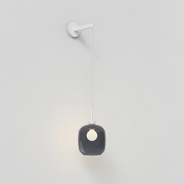 A white wall-mounted light fixture with a grey glass shade and an exposed bulb