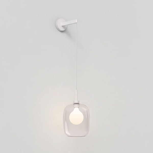 White wall light with a clear glass shade and a glowing bulb