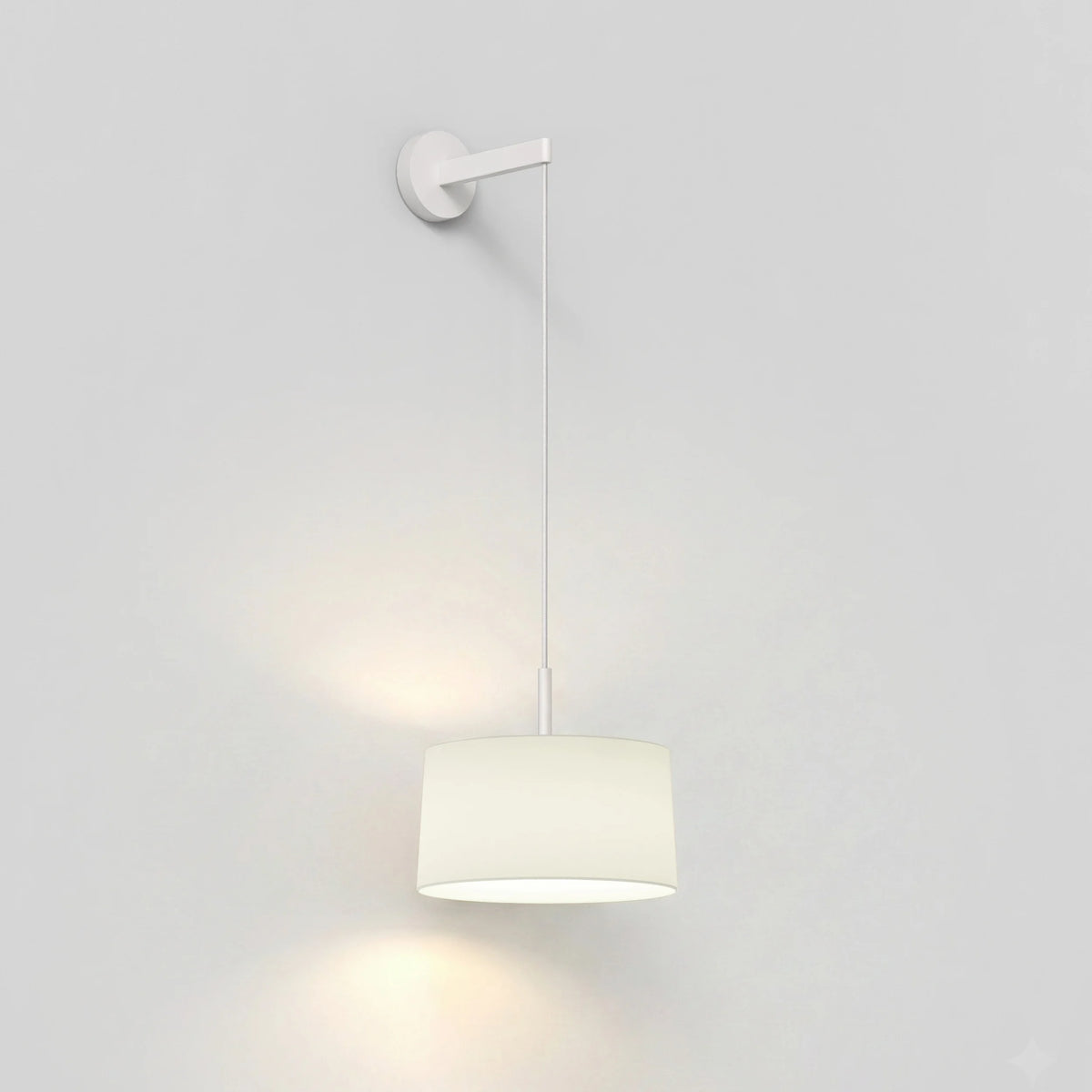 White wall sconce with a cylindrical fabric shade hanging from a thin rod, casting a warm glow downwards