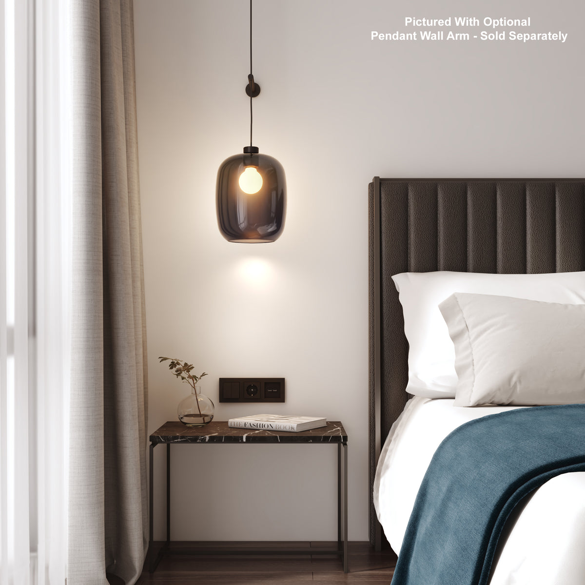 Pendant light with a dark glass shade hanging above a marble-top nightstand next to a bed