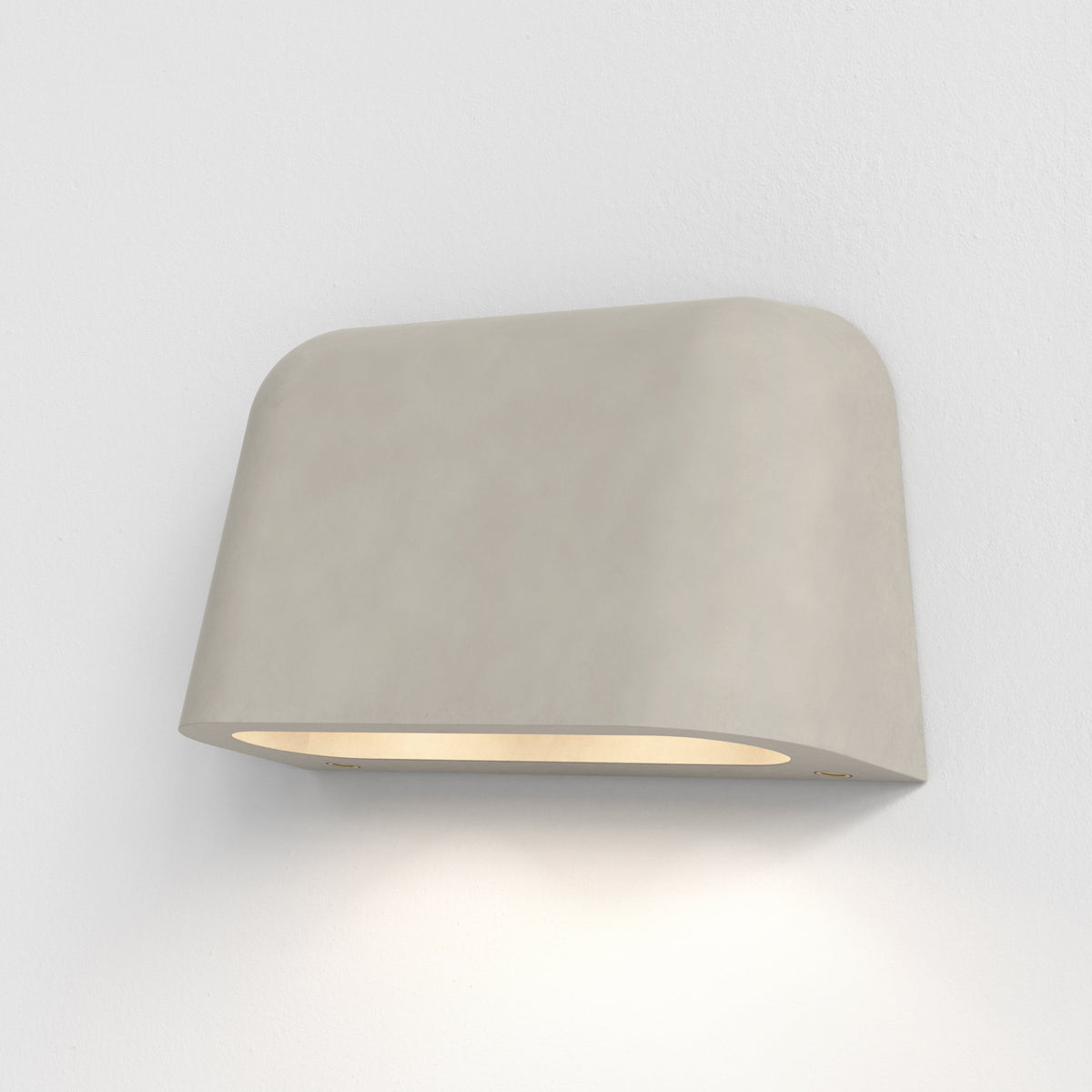 Light grey wall light with a curved top and bottom, emitting a warm glow downwards onto a white wall