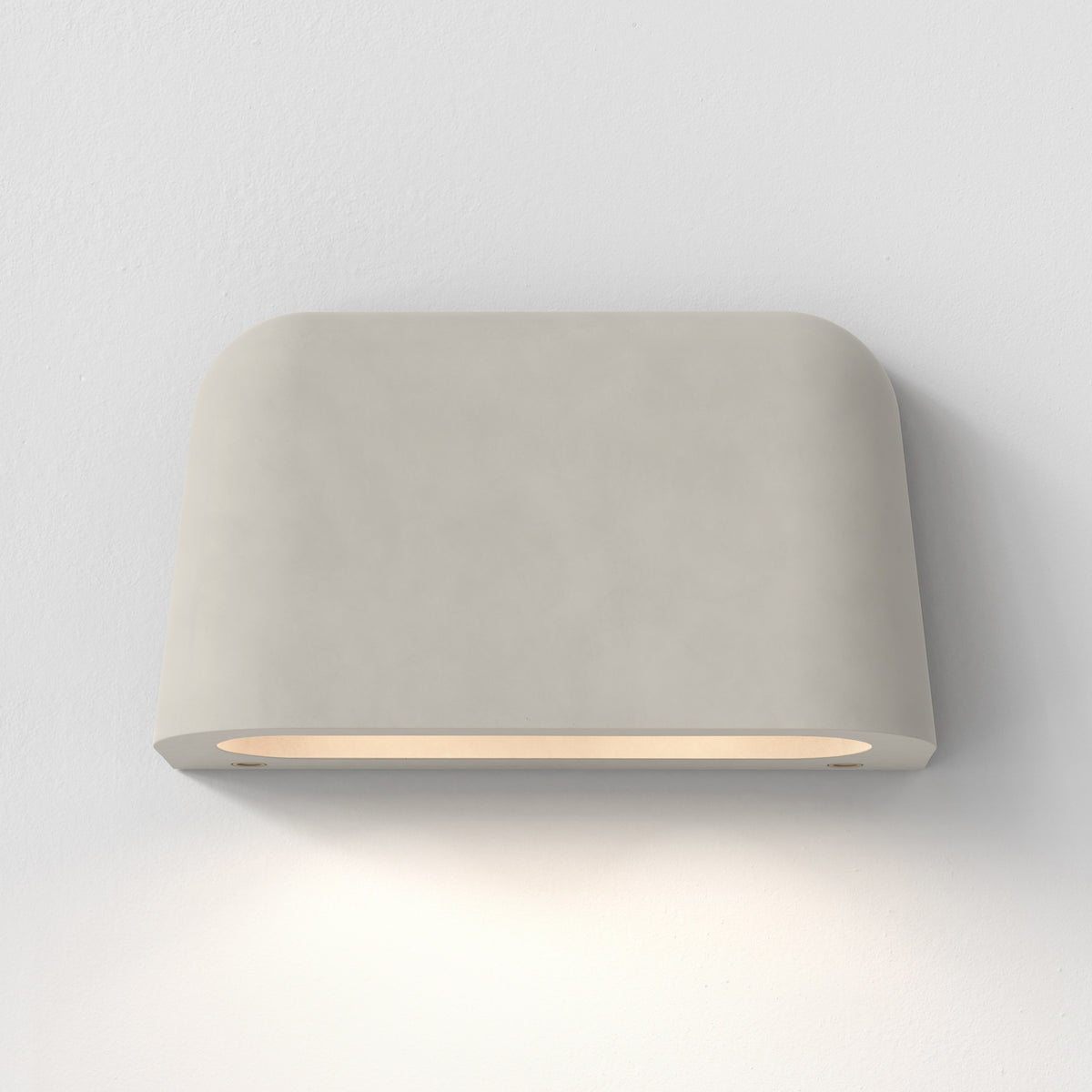 Rectangular light grey wall sconce with rounded corners, emitting a warm glow downwards onto a white wall