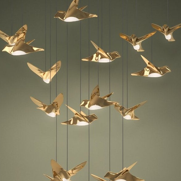 Close-up of several golden bird-shaped lights with illuminated undersides