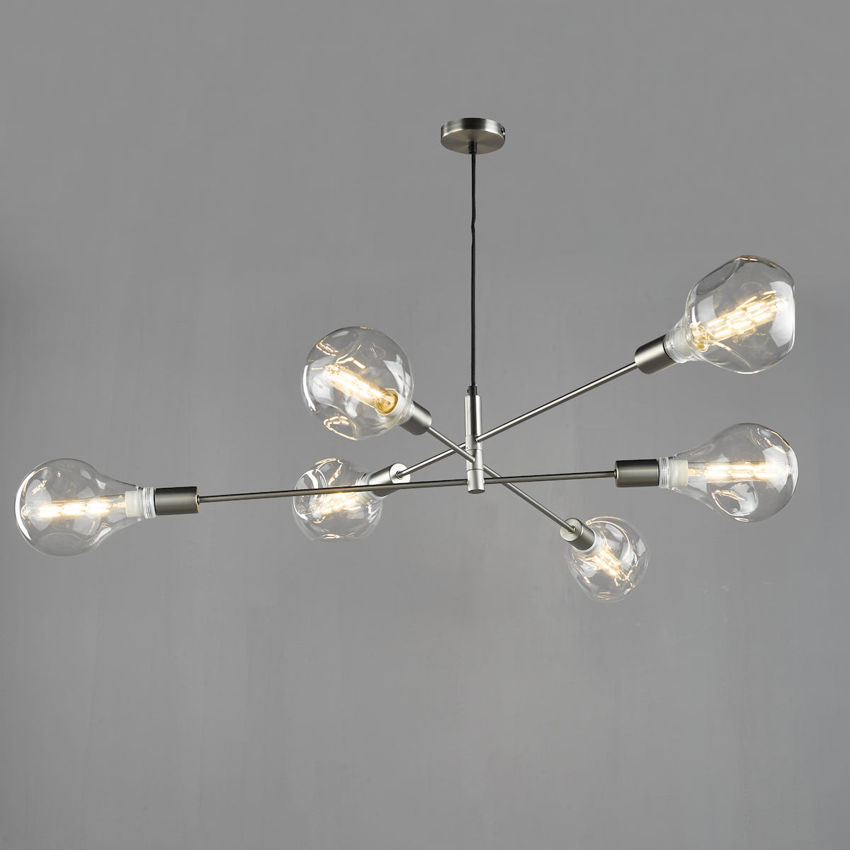 Modern chandelier with six clear, exposed bulbs on brushed nickel arms, against a gray background.