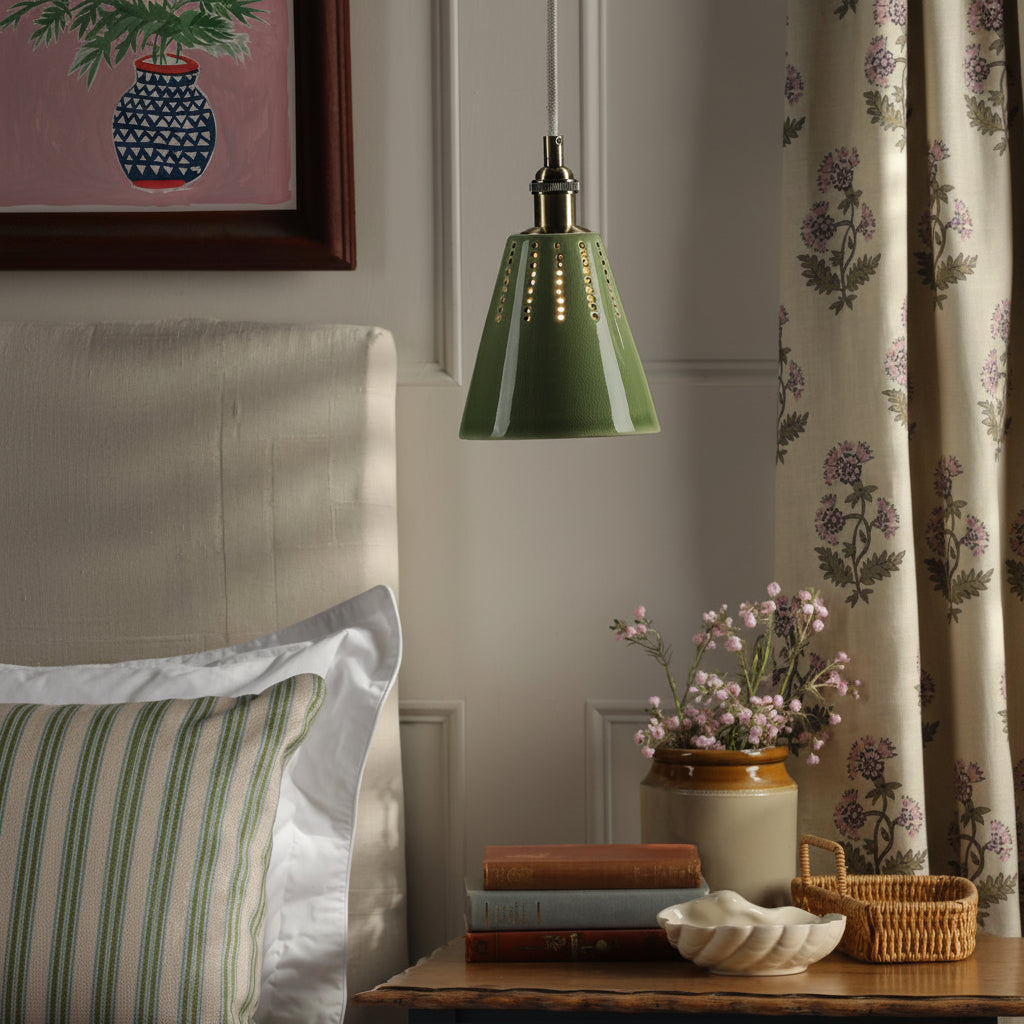 Joules Allington green glazed ceramic pendant light with antique brass fitting hanging above a bedside table
