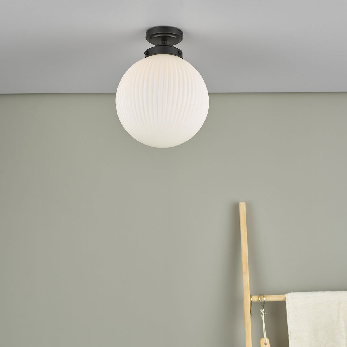A white fluted glass globe ceiling light with a black base, mounted on a light gray ceiling.