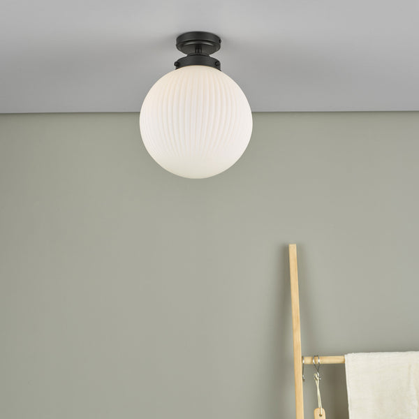 A white fluted glass globe ceiling light with a black base, mounted on a light gray ceiling.