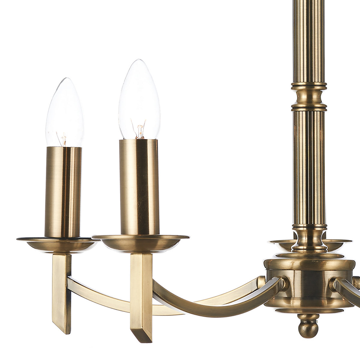 Close-up of a brass chandelier with two candle-shaped bulbs and a fluted central column.