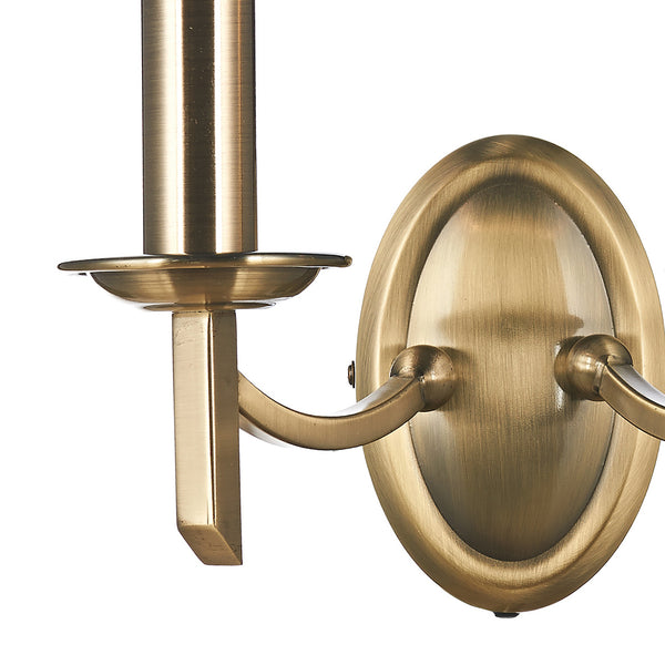 Close-up of a brass wall sconce with an oval backplate and two curved arms.