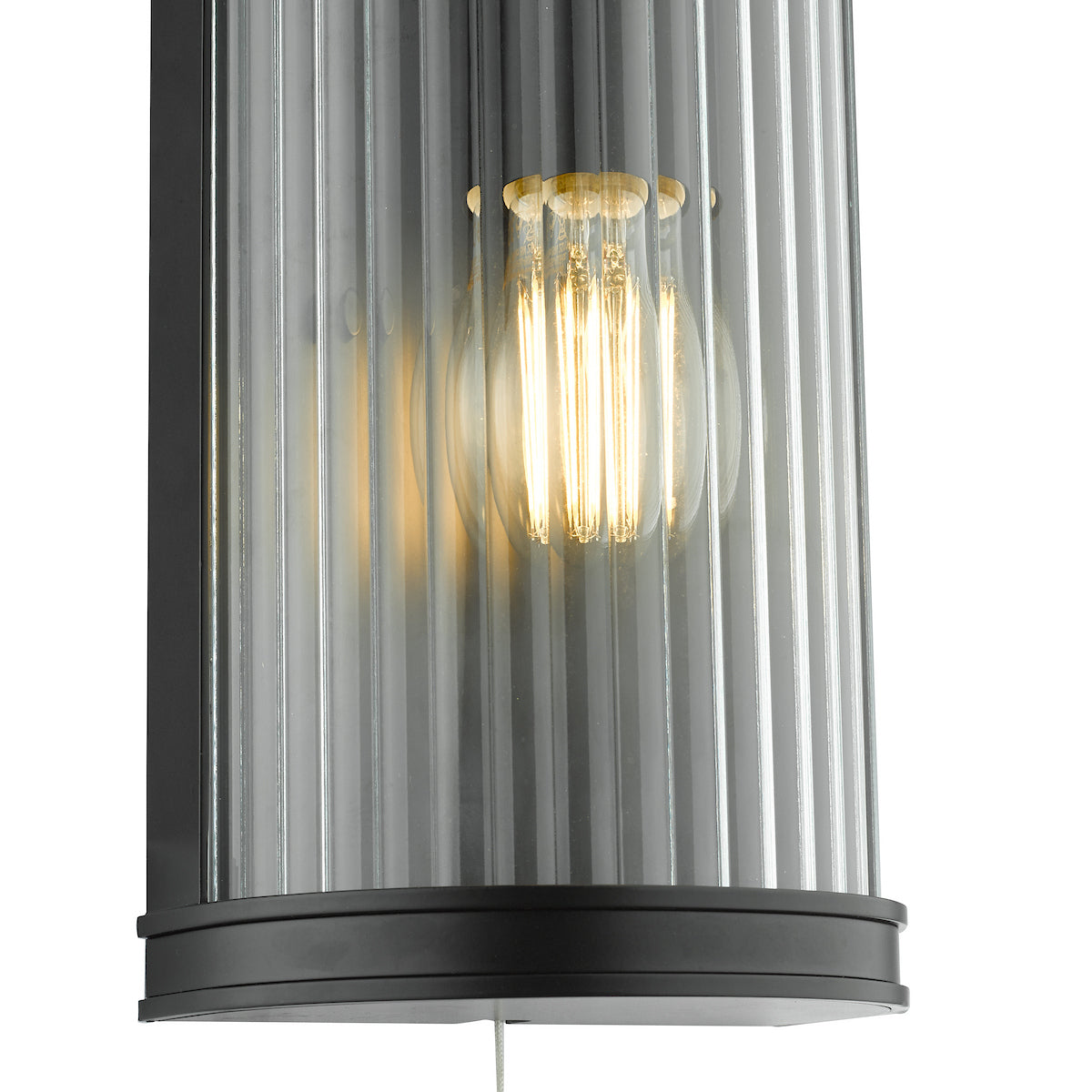 Close-up of a modern wall sconce with a ribbed glass shade and an exposed filament bulb.