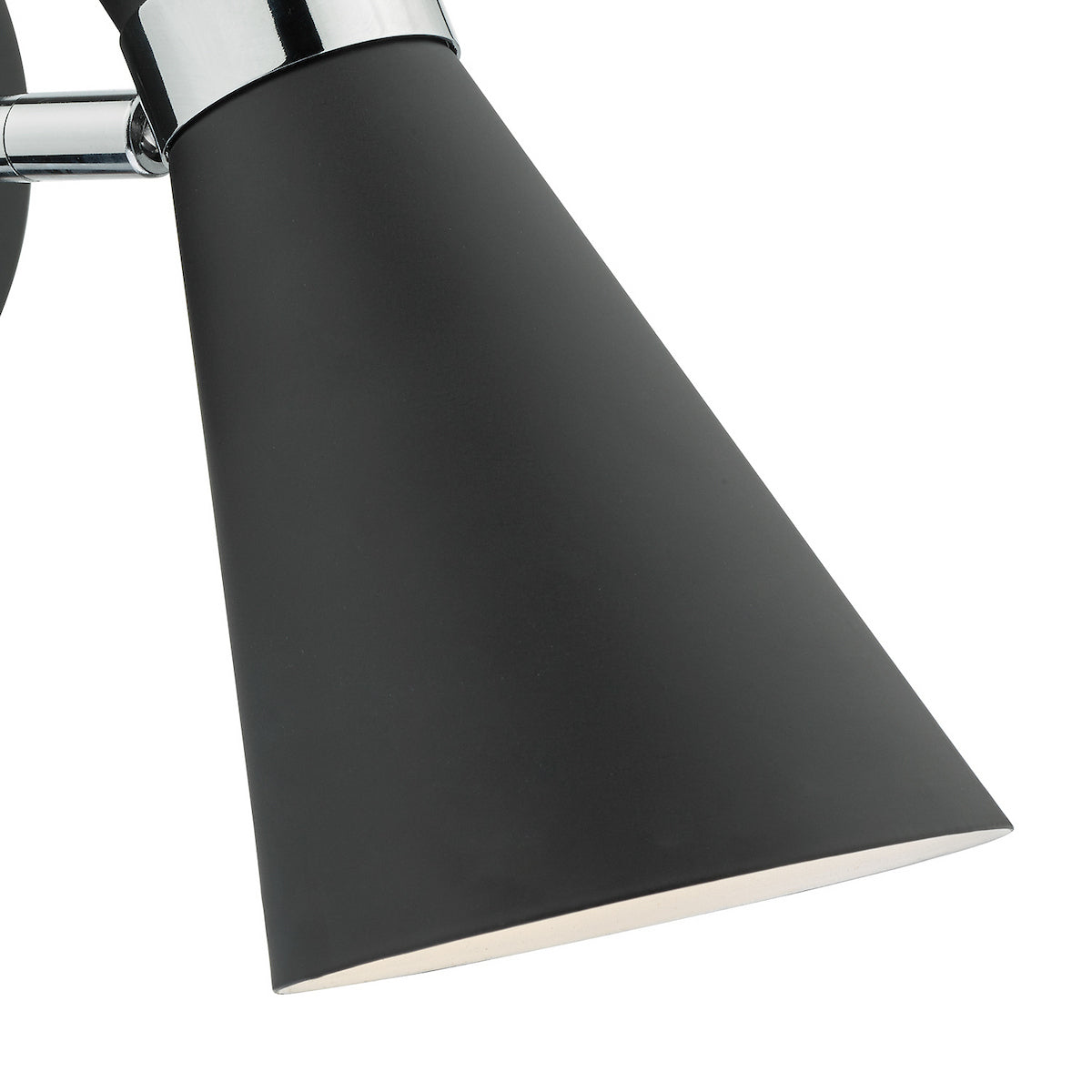Close-up of a black conical lamp shade with a chrome accent, emitting a soft glow.