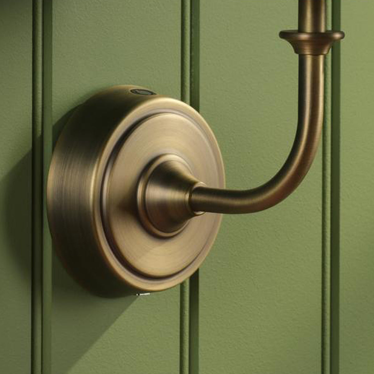 Joules Apsley rechargeable wall light base in matt antique brass mounted on a green paneled wall