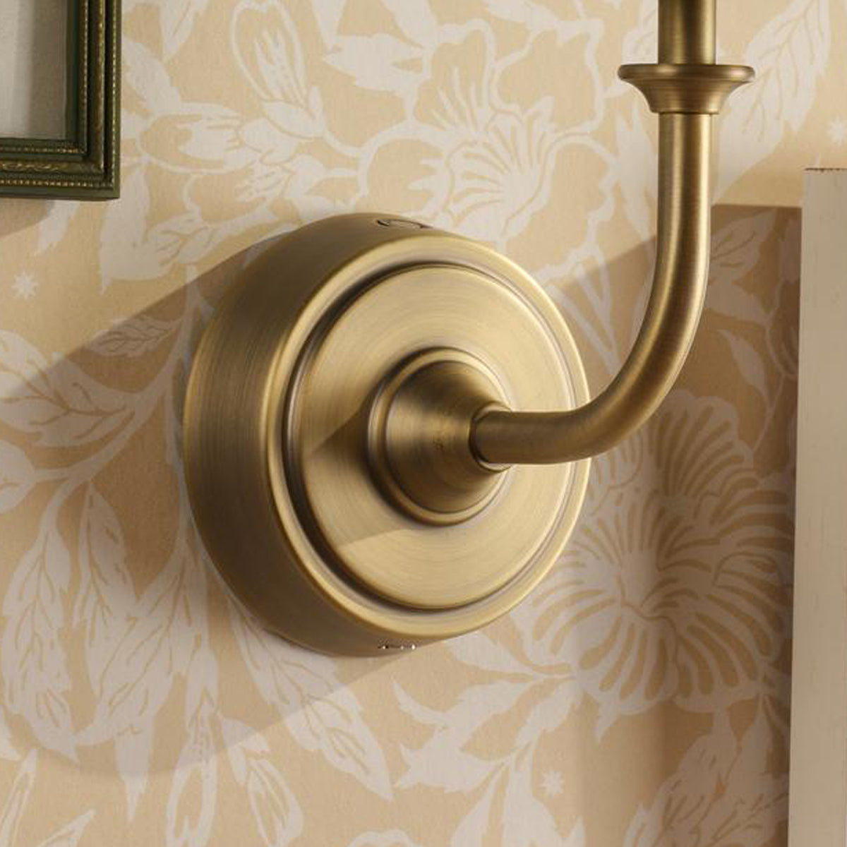 Joules Apsley rechargeable wall light in matt antique brass mounted on floral wallpaper