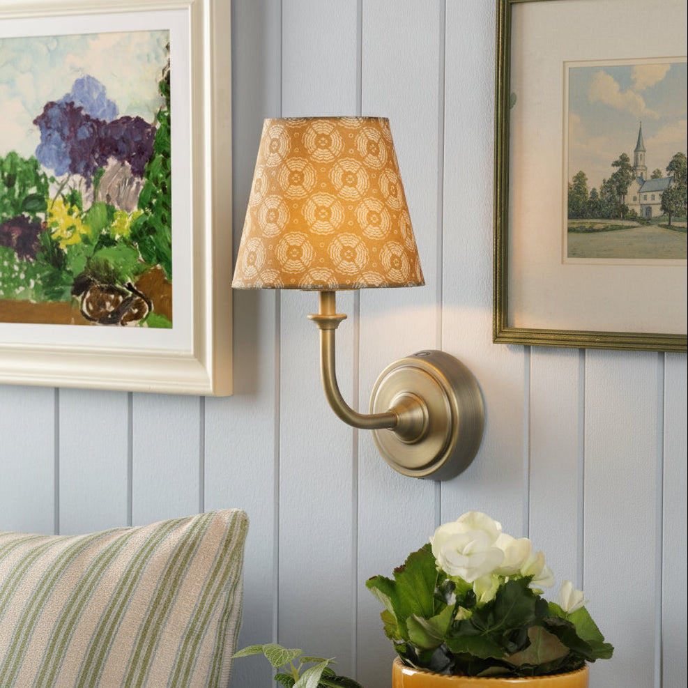 Joules Apsley rechargeable wall light in matt antique brass with a patterned yellow cotton shade