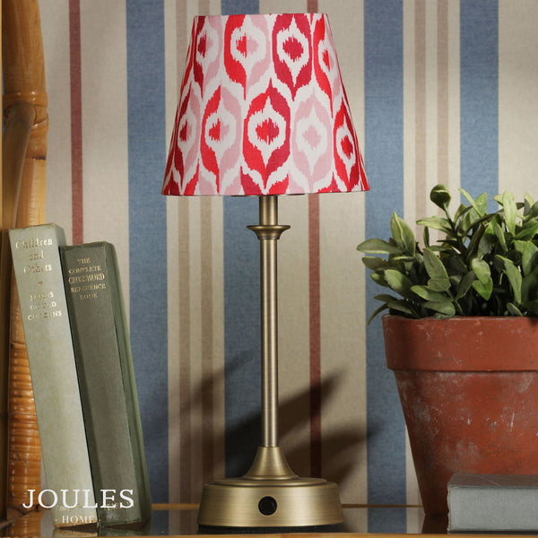 Joules Home table lamp with a red and pink ikat patterned shade on a brass base