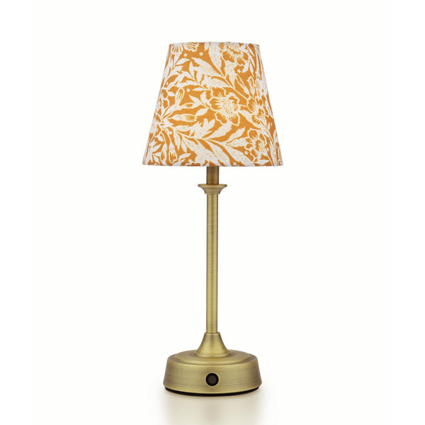 Table lamp with a brass finish base and a tapered shade featuring a white and mustard yellow floral pattern
