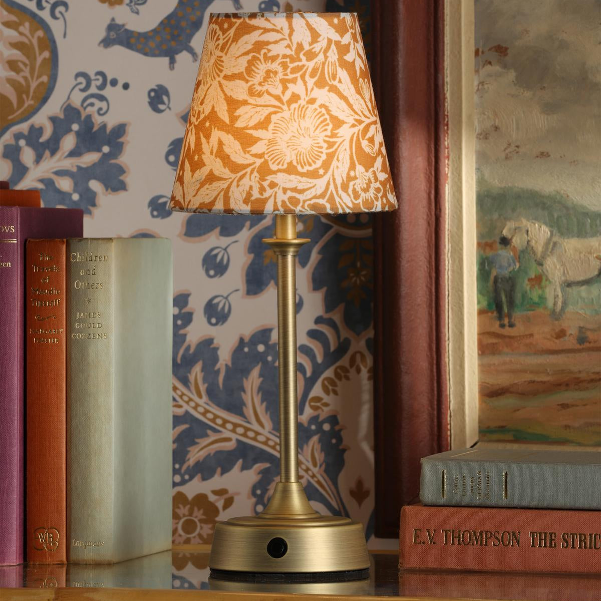 Joules Apsley rechargeable table lamp with antique brass base and yellow floral cotton shade on a bookshelf