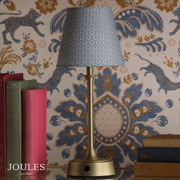 Joules Home brass table lamp with a blue patterned fabric shade next to stacked books