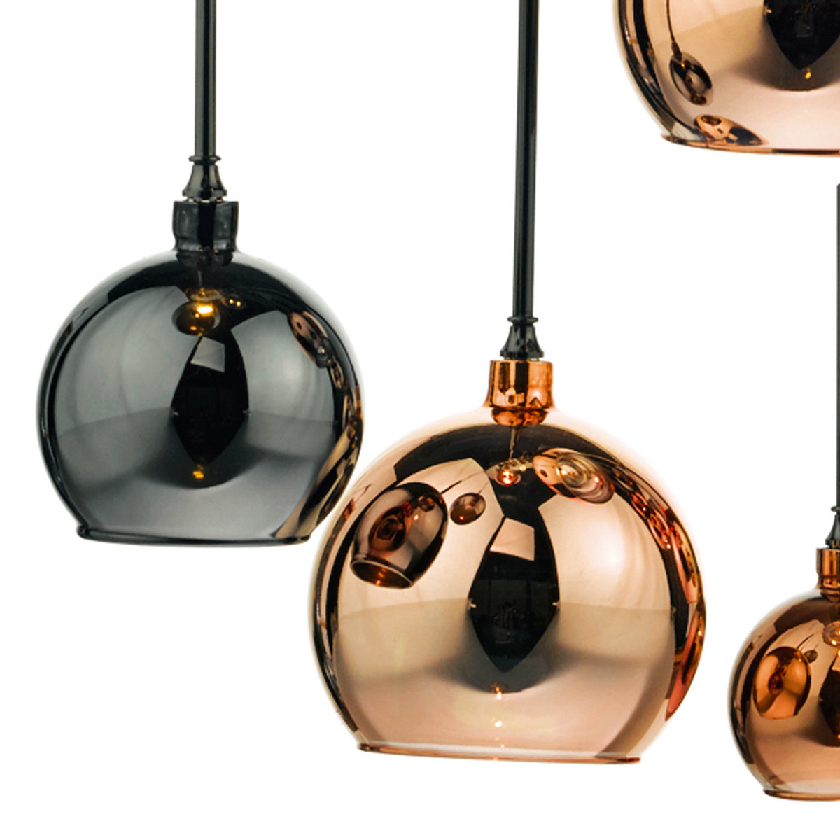Close-up of three pendant lights, one black and two copper, with reflective surfaces.