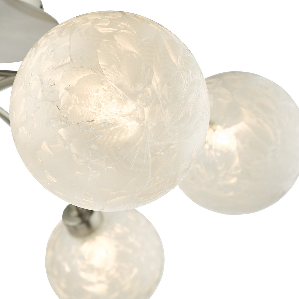 Close-up of a modern light fixture with three frosted glass globe shades, illuminated from within.