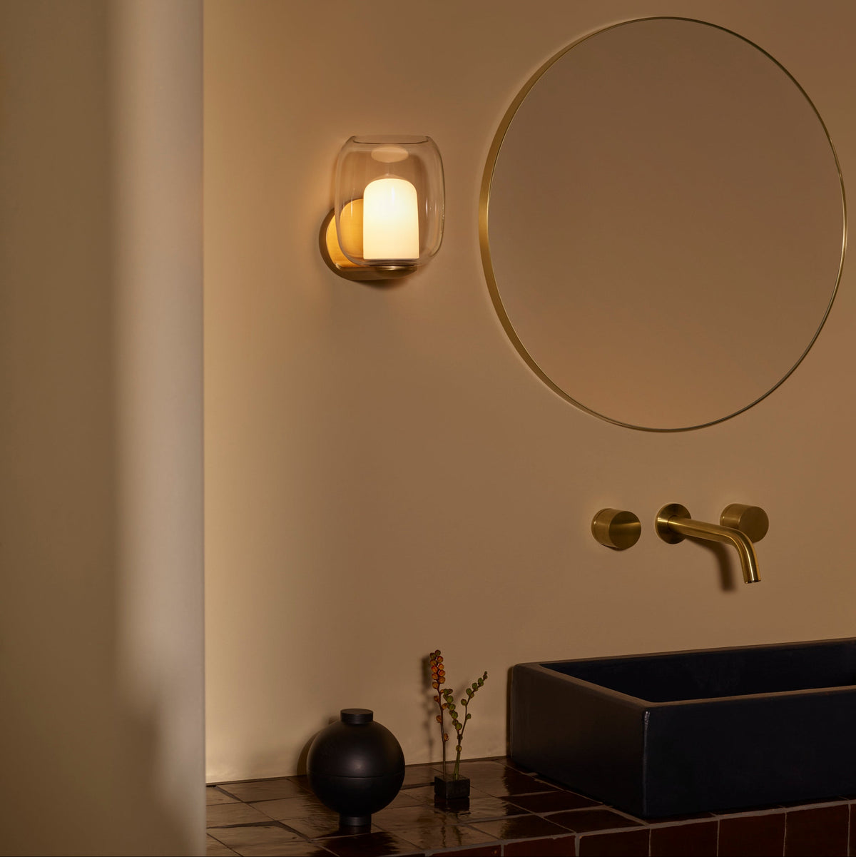 Bathroom with a black sink, a round mirror, and a wall-mounted light fixture