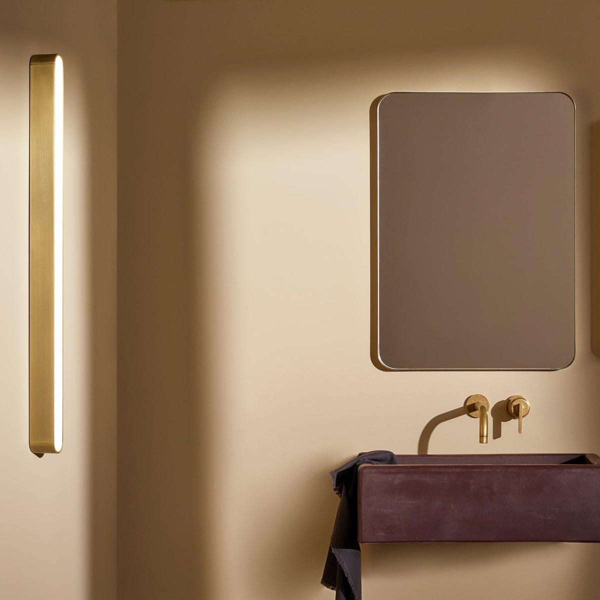 Bathroom with a rectangular mirror, a dark red sink, and brass fixtures. A vertical light fixture is on the left
