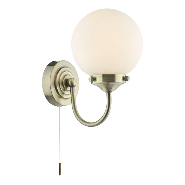 Antique brass wall light with a curved arm and a spherical opal glass shade, featuring a pull cord switch.
