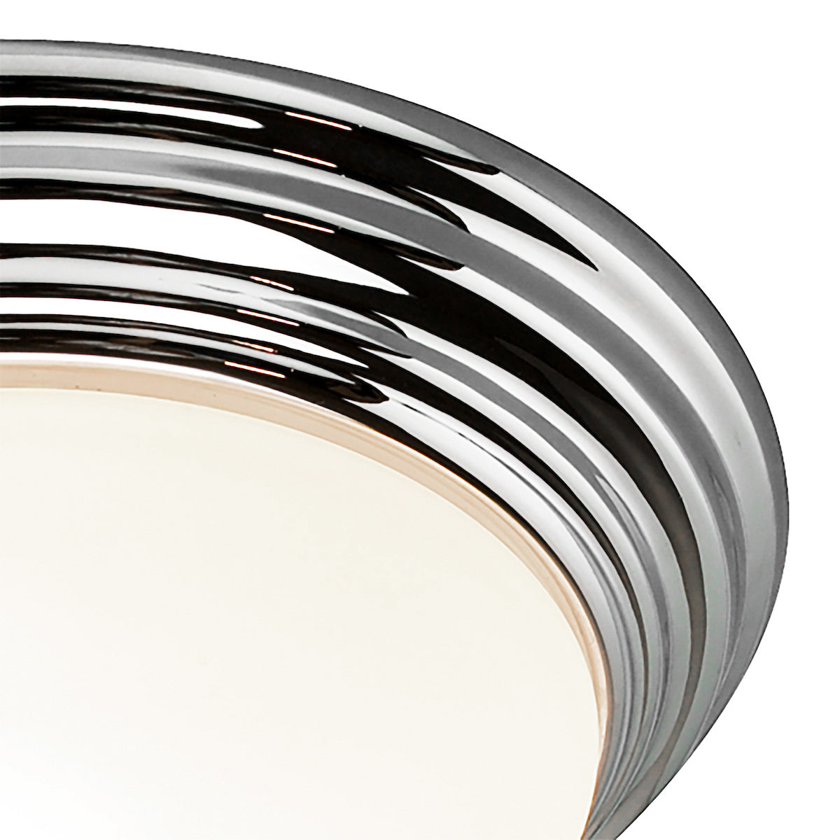 Close-up of a chrome-plated light fixture with a white diffuser, showing reflective bands.