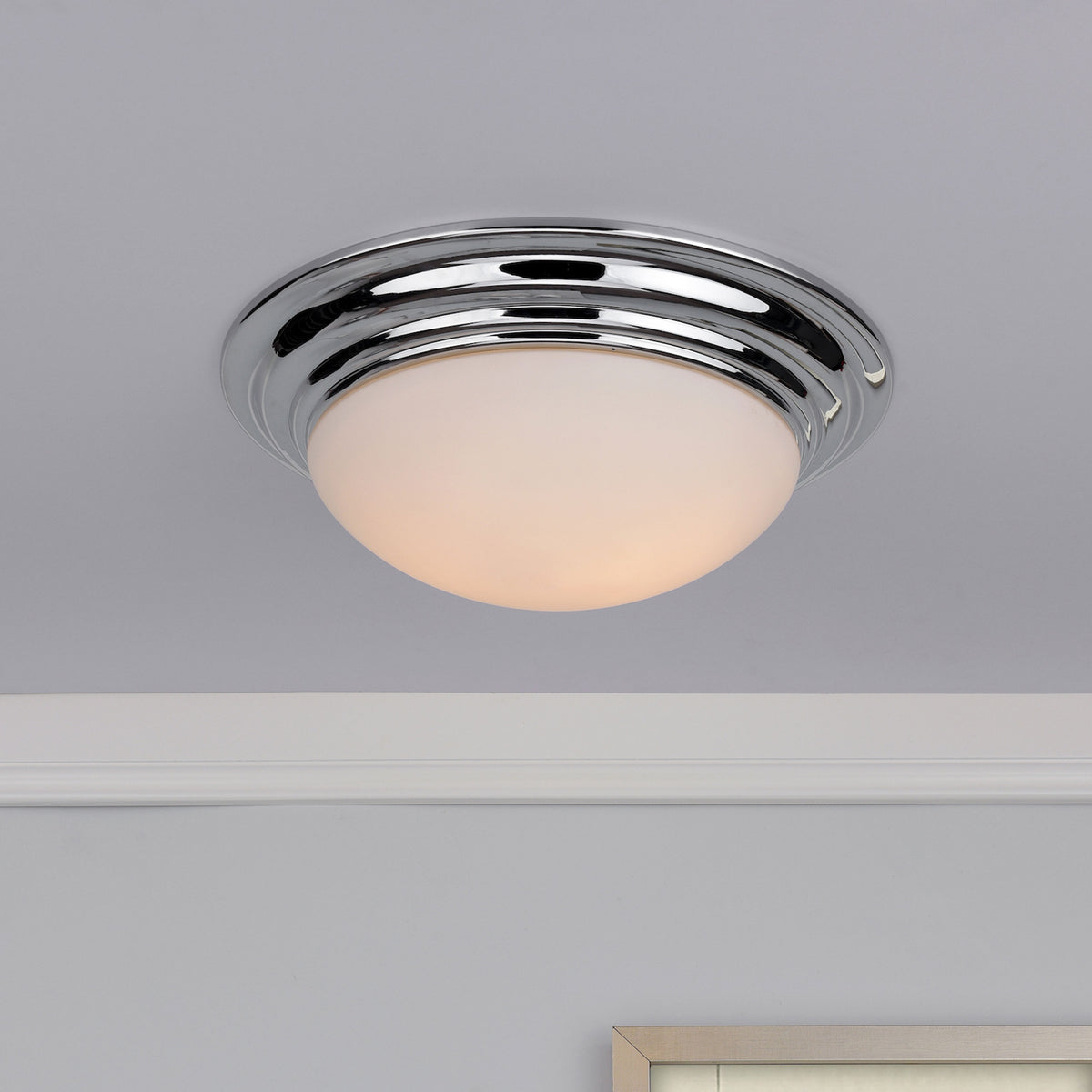 Chrome flush mount ceiling light with an opal glass shade, illuminating a room with soft light.
