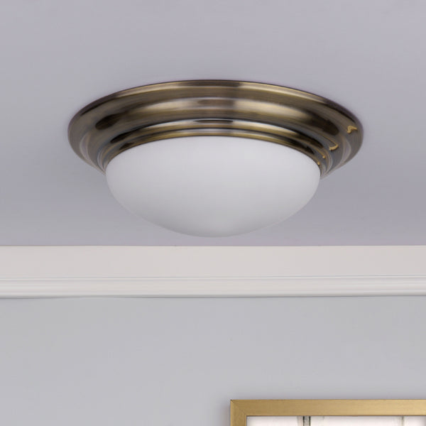 Close-up of a ceiling light fixture with a brass base and a white dome-shaped glass shade.