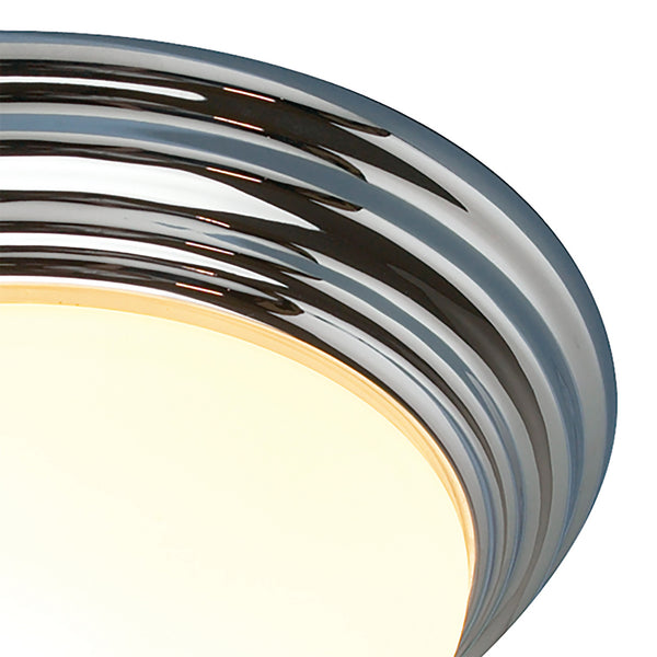 Close-up of a chrome light fixture with a glowing white diffuser.