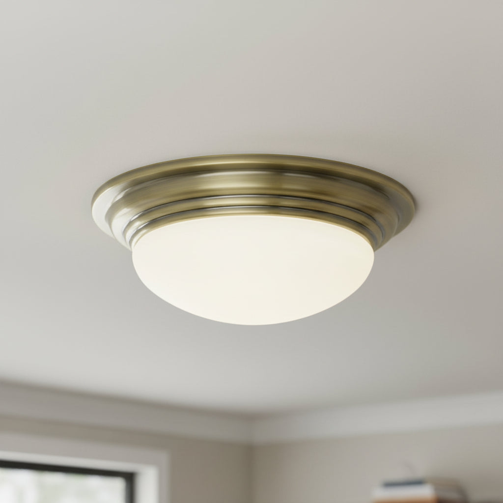 Antique brass flush mount ceiling light with a frosted glass dome shade.