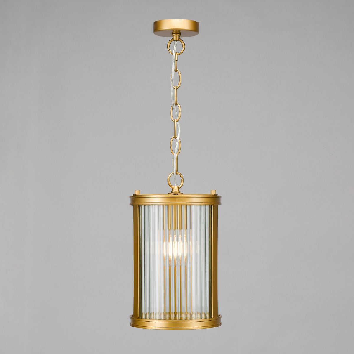 Gold pendant light with a cylindrical reeded glass shade and a visible bulb