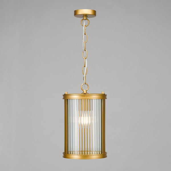 Gold pendant light with a cylindrical reeded glass shade and a visible bulb