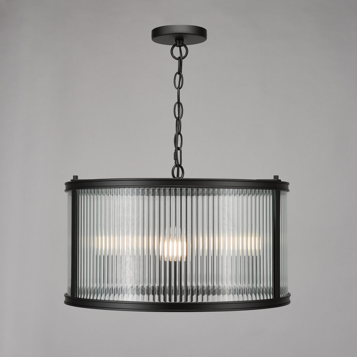 Black metal chandelier with a fluted glass drum shade and three visible light bulbs