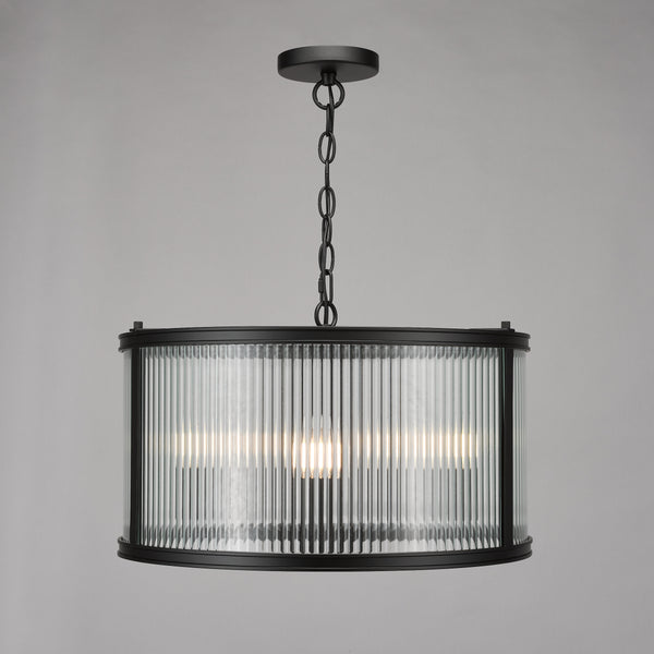 Black metal chandelier with a fluted glass drum shade and three visible light bulbs