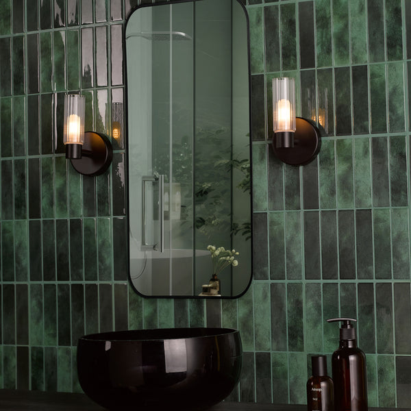 Bathroom with dark green subway tiles, black mirror, black basin, and two wall-mounted lights