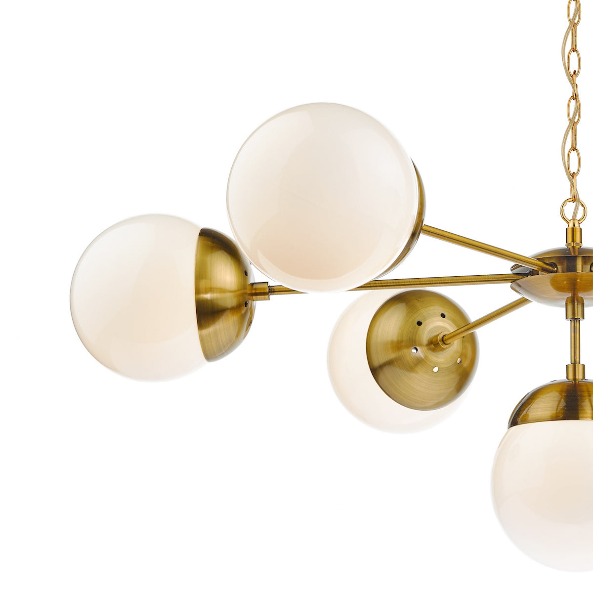 Close-up of a brass chandelier with multiple white globe lights, some partially covered by brass caps.