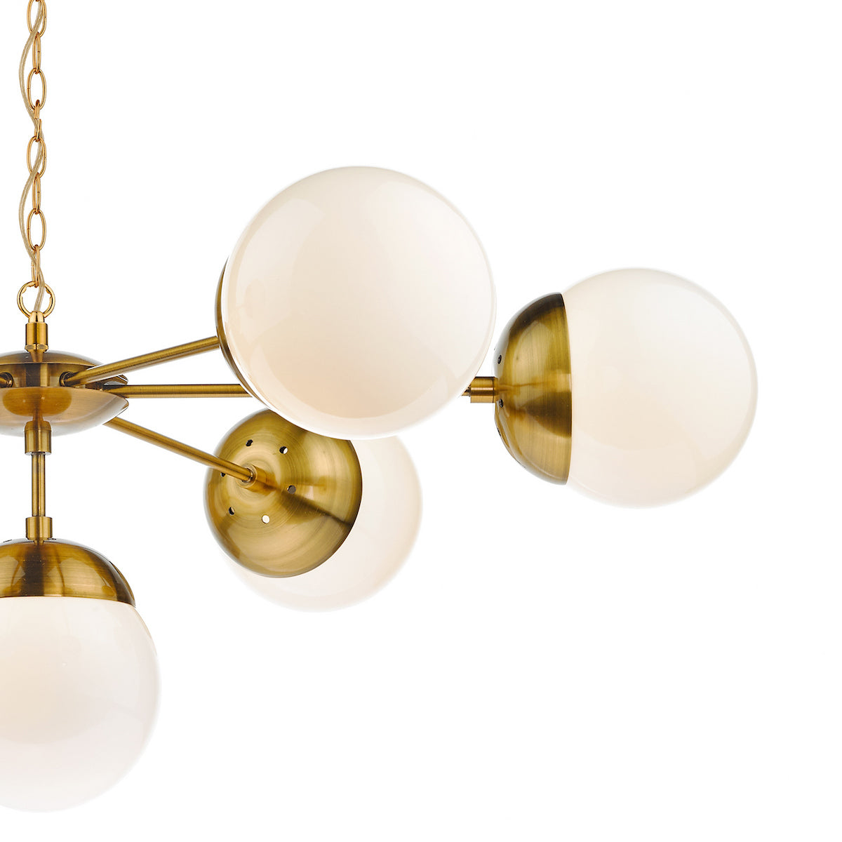Close-up of a modern brass chandelier with multiple white globe lights, against a white background.