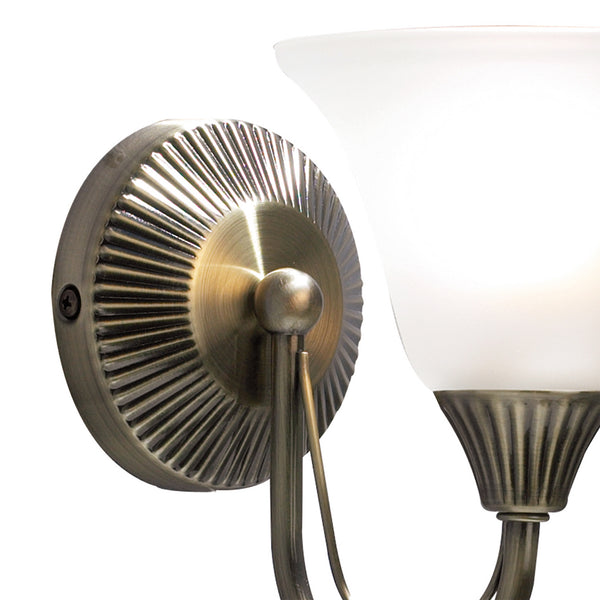 Close-up of a brass wall sconce with a ribbed circular base and a frosted glass shade.