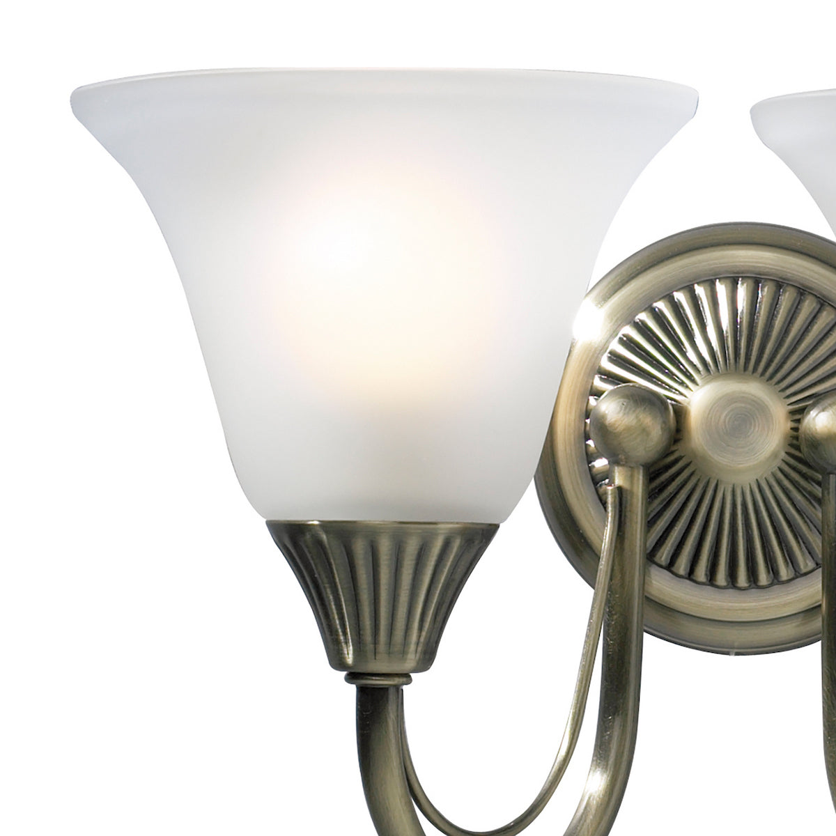Close-up of a wall sconce with a frosted glass shade and an antique brass finish.