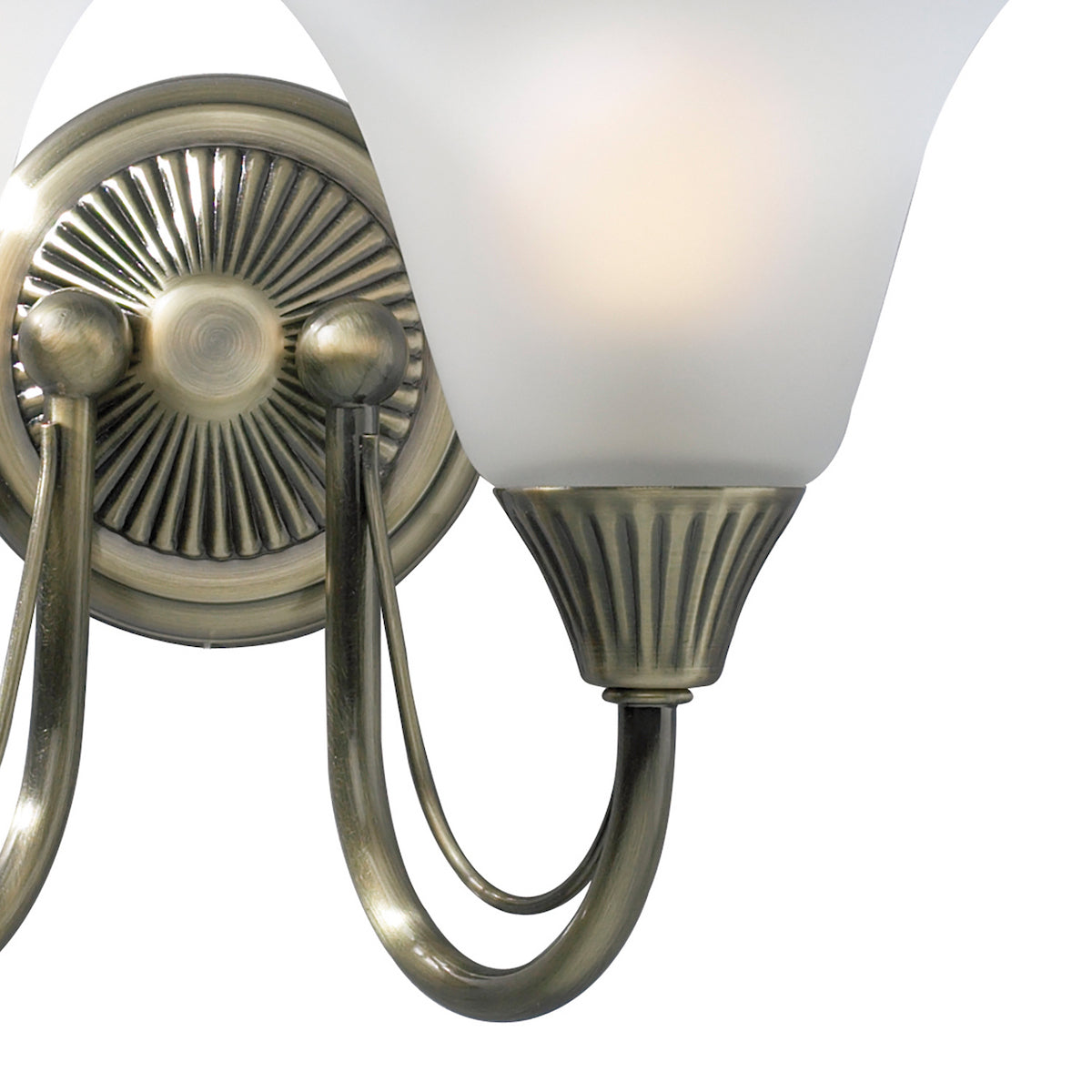Close-up of an antique brass wall sconce with a frosted glass shade and decorative base.